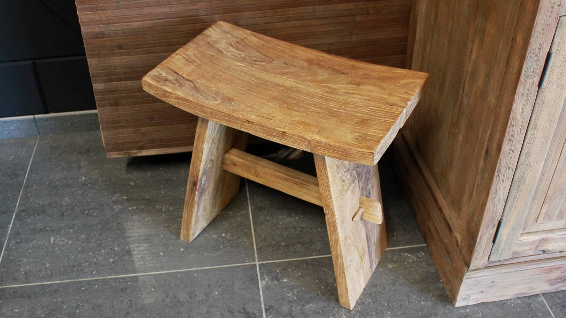 Klein teakhouten krukje met rond zitvlak.